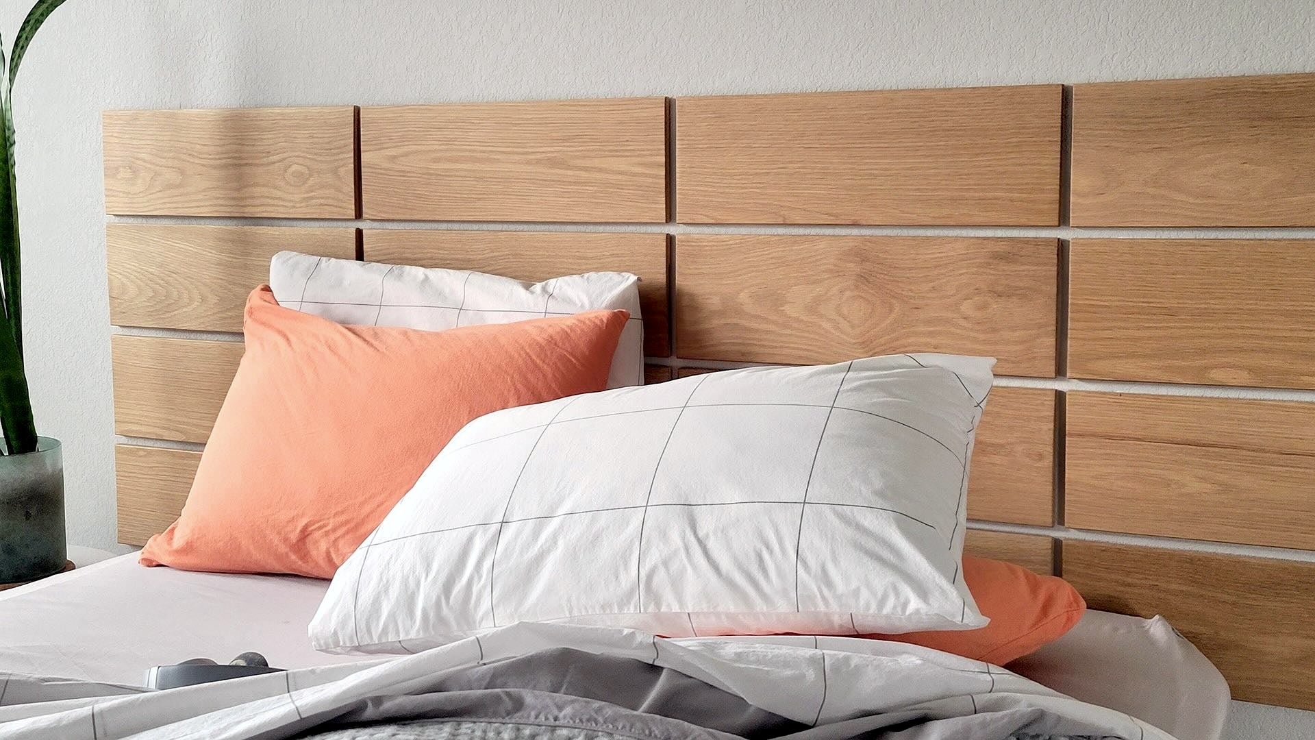 TALAYA Solid Ground tiles in Honey Oak finish installed in an evenly spaced grid pattern above a bed with orange pillows and grey and white bedding