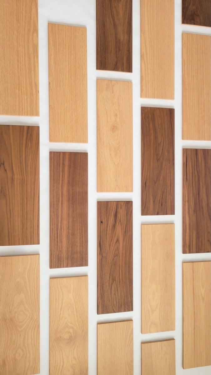 TALAYA Solid Ground tiles in Honey Oak and Walnut Mocha finishes arranged in a vertical offset brick pattern on a wall, shot at an angle