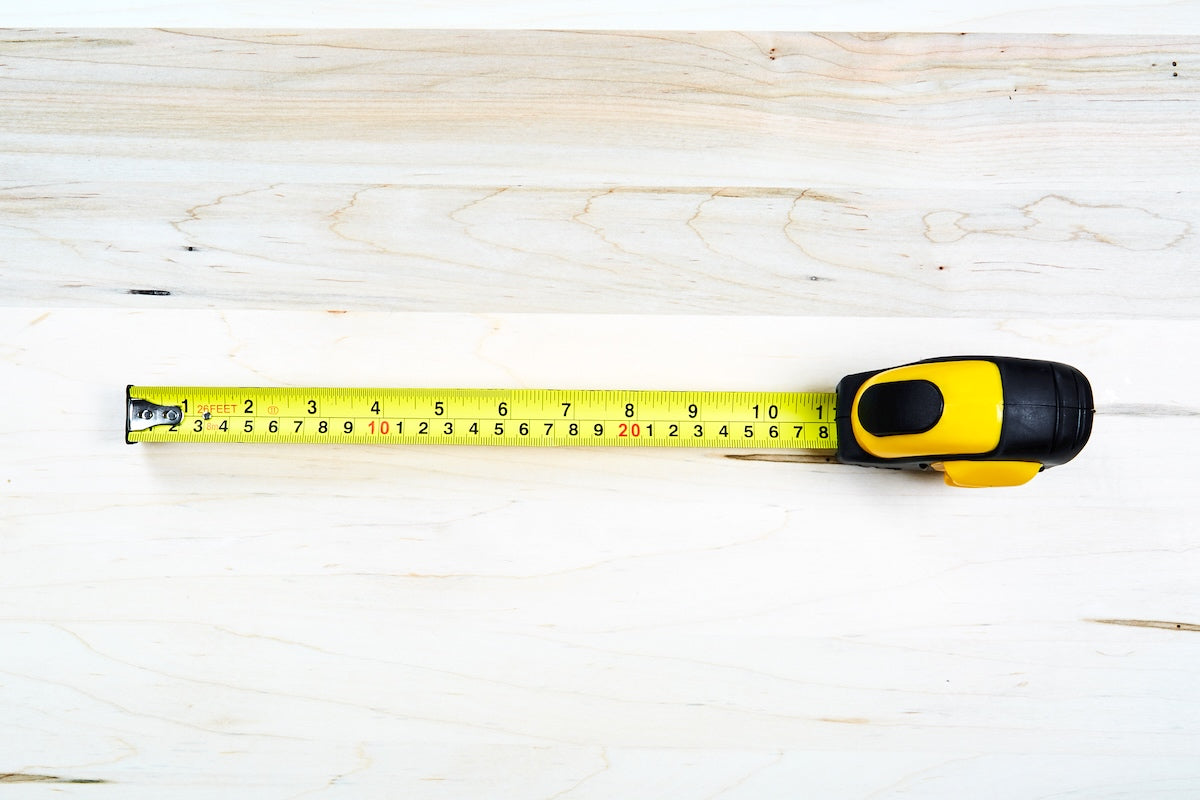 Close-up overhead view of a tape measure on a light wood surface